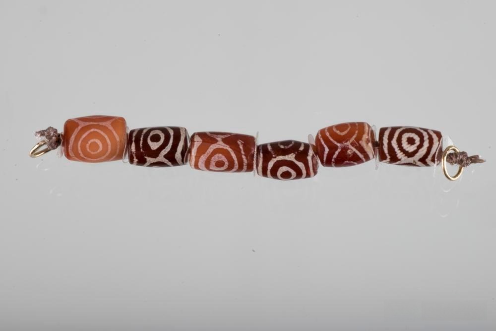 Jewelry featuring white-patterned etched beads, part of the British Museum’s collection, showcasing ancient craftsmanship.