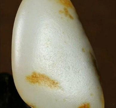 A close-up of natural Hetian seed jade showing "sweat pores" and skin.