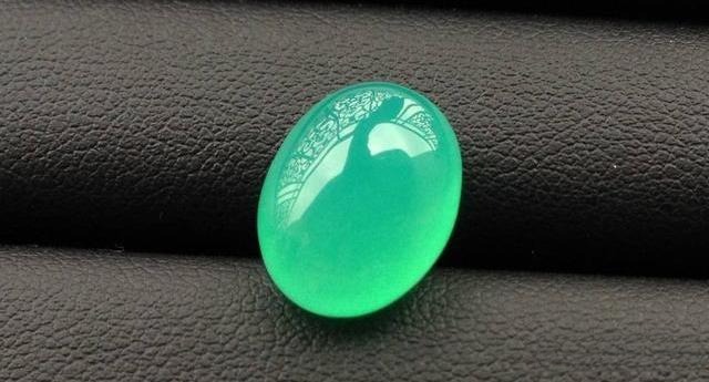 A close-up view of a translucent, dyed green Chalcedony gemstone displaying unnaturally uniform color saturation.