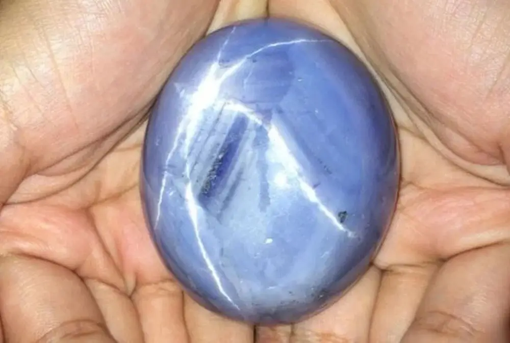 Hands holding the 1404.49ct "Star of Adam," the world's largest star sapphire, discovered in Sri Lanka.
