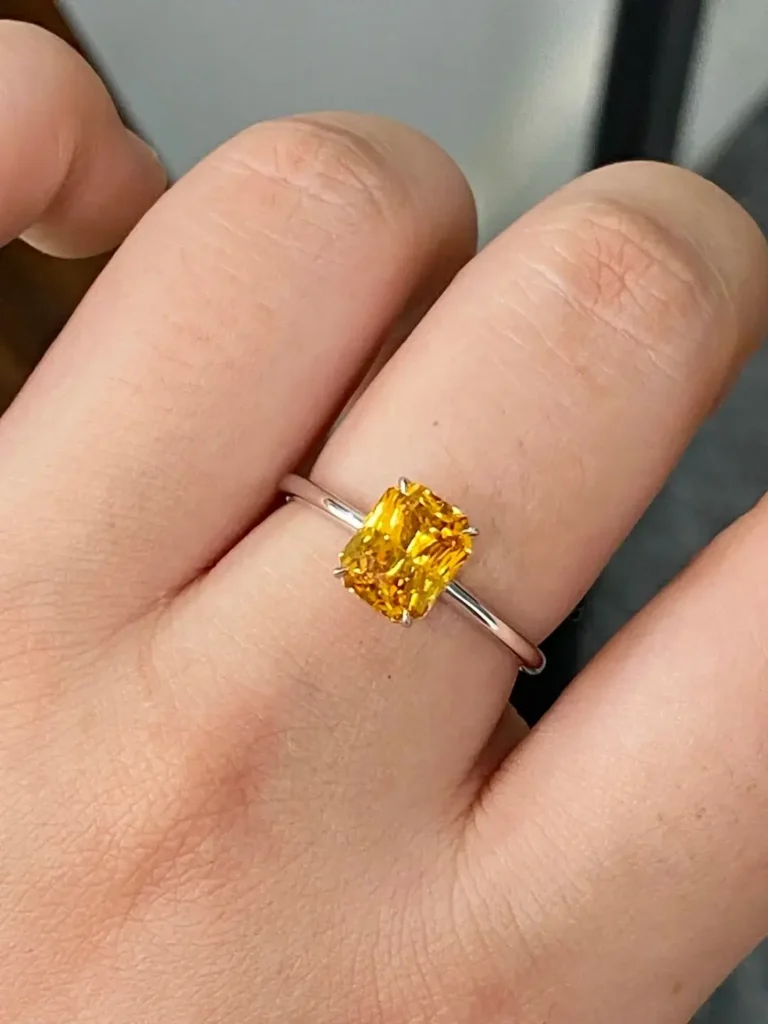 A 4-carat radiant cut yellow sapphire set in a classic four-prong gold ring mounting.
