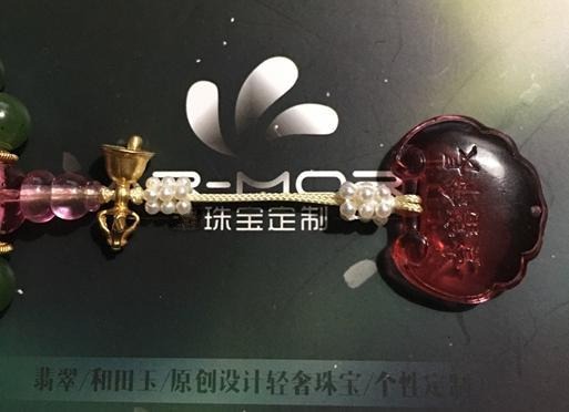 Close-up showing two pearl flower balls threaded onto the cord ends before attaching the glazed glass lock pendant.