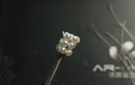 Close-up showing three pearl rings stacked and secured at one point with a thread knot, forming the flower ball base.