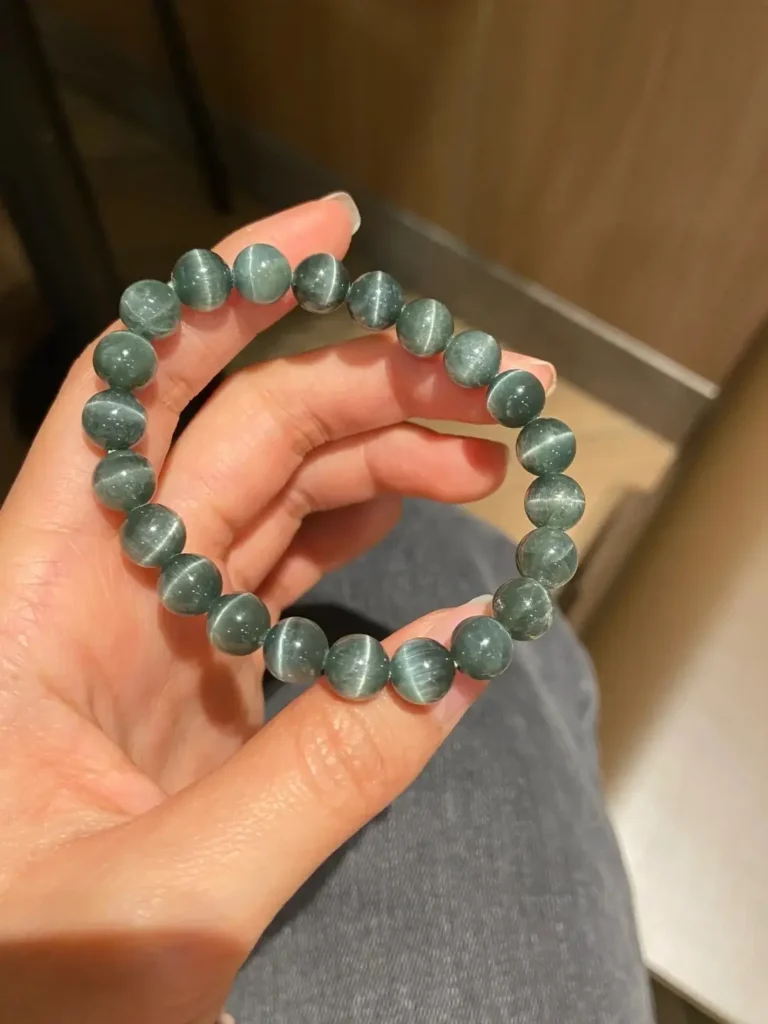 Green cat’s eye apatite bracelet displaying chatoyancy, with polished beads highlighting internal fibrous structures.