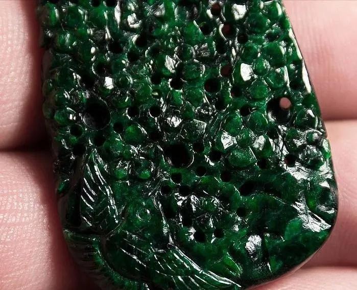 Rough, opaque dark green stone with black mineral spots and a dry, crumbling texture.
