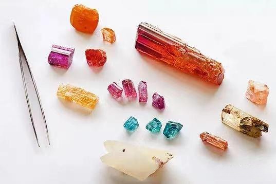 A group of natural topaz crystals in shades of sherry, yellow, pink, and pale blue.