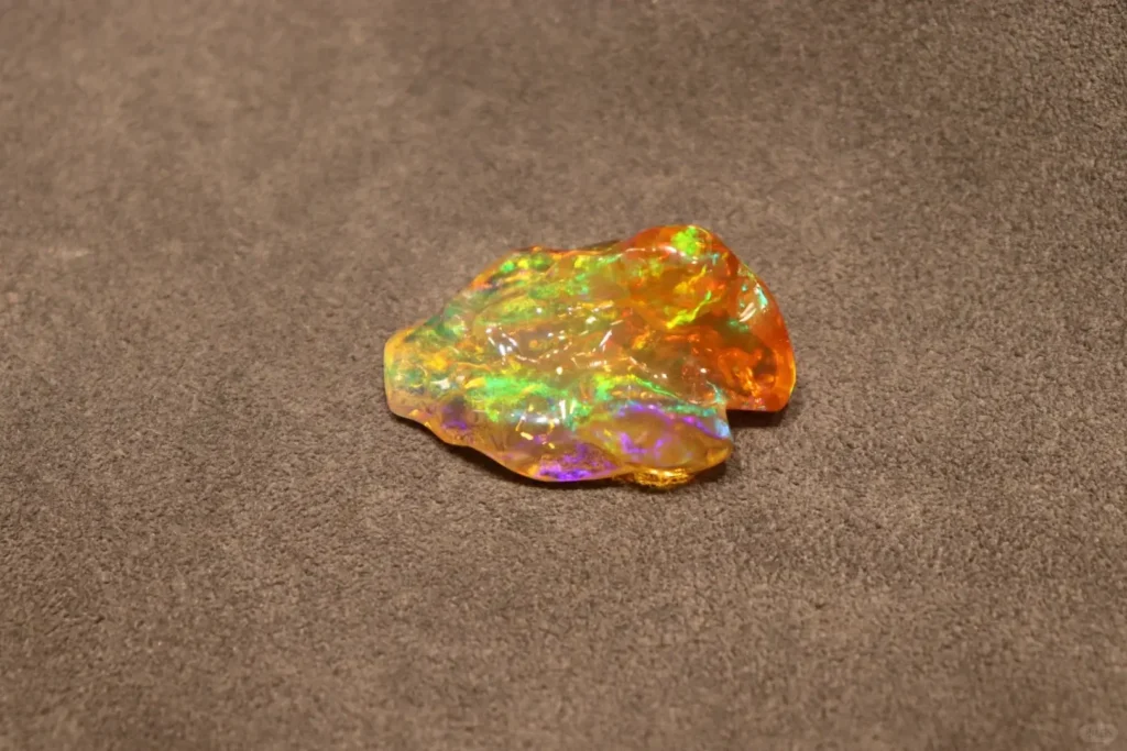 Transparent Precious Fire Opal showing rainbow play-of-color and flowing spectral flashes.