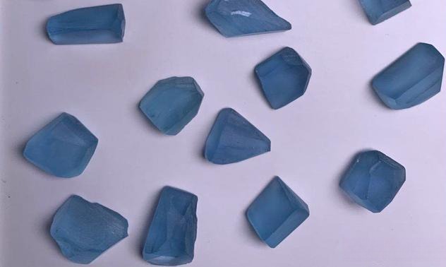 A collection of uncut, deep blue beryl crystals exhibiting high saturation and natural raw textures.
