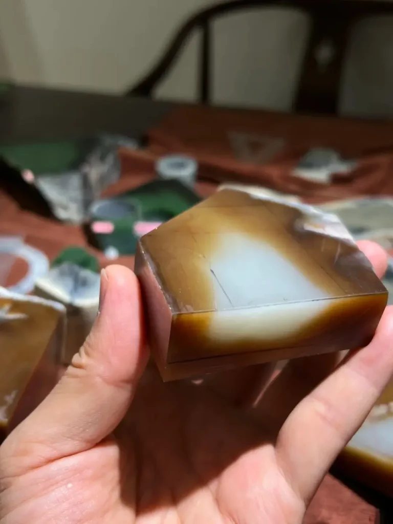 A sliced Hetian jade stone showing a distinct boundary between white nephrite and brown sugar-colored zones.