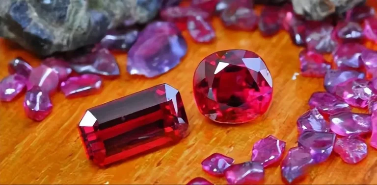 Rough and faceted red rubies in a host rock with green pyroxene, representing Thailand gemstones.