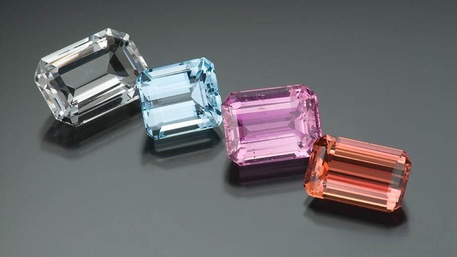 Four topaz gemstones in blue, yellow, and sherry hues, showcasing extreme price differences.