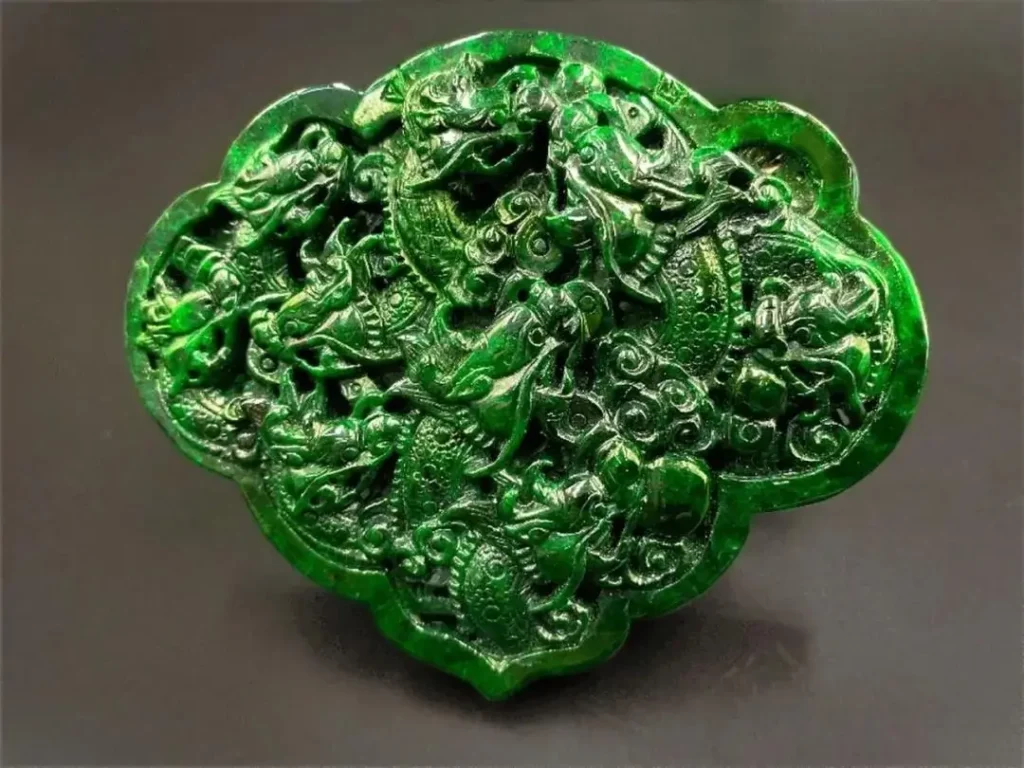 Polished dark green Gan Qing jade with an unnatural oily surface and visible surface pits.