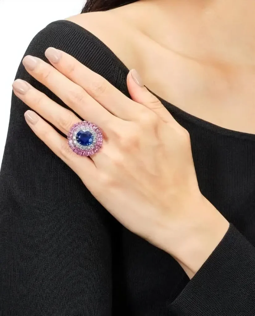 A hand wearing a natural unheated Thai blue sapphire ring accented with diamonds and pink corundum.