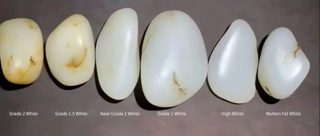 Comparison of white Hetian jade stones showing variations in color tones and surface oiliness.